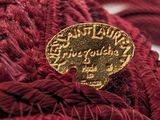 a red scarf with a gold button on top of it