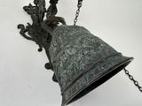 a metal bell hanging from a chain on a wall