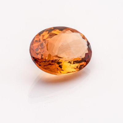 a close up of a faceted citrine gemstone on a white surface