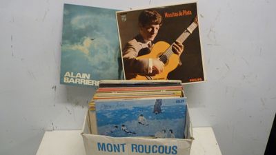 une boîte remplie de disques posée sur une table, avec une guitare à côté