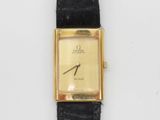 un gros plan d'une montre en or avec un bracelet en cuir noir