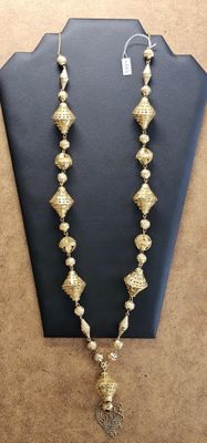 gold plated beaded necklace with a tassel on a mannequin