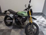 une moto verte et noire garée sur un sol à damier
