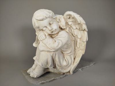 une statue représentant un ange assis sur un rocher