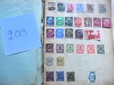 un livre ouvert sur lequel figurent des timbres et un morceau de papier posé sur la couverture