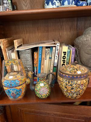 many vases and books on a shelf in a room