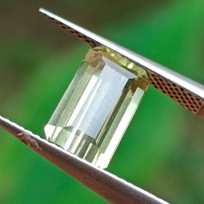 un diamant vert maintenu par une pince à épiler