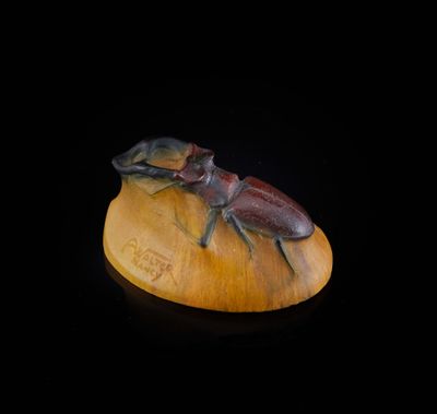 un gros plan d'une statue représentant deux scarabées posés sur un morceau de bois