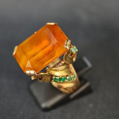 une image représentant une bague en or surmontée d'une pierre orange