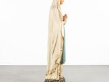 a statue of a woman in a white robe is standing on a rock