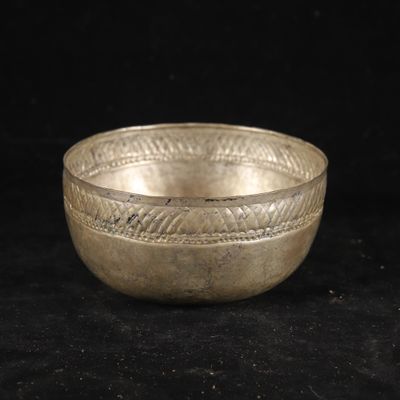 a silver bowl on a black surface with a black background