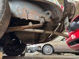 a red car that is under a car in a garage