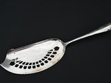 a silver spoon with holes on it on a black surface