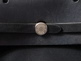 the back of a black bag with a metal button on it