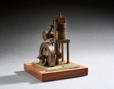 une petite maquette de machine à vapeur posée sur un socle en bois