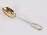 a silver spoon with a gold spoon handle on a white surface