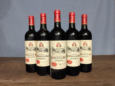six bottles of red wine are lined up on a wooden table