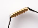 a close up of a gold plated watch on a black leather strap