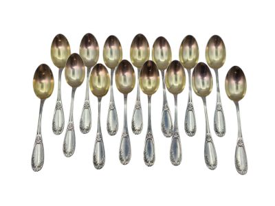 six cuillères en argent sont alignées sur une surface blanche