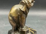 statue of an elephant on a marble base with a black background
