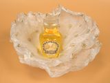 a small bottle of honey sitting on a white flower