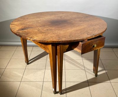 une table en bois avec un tiroir en dessous, posée sur un sol carrelé