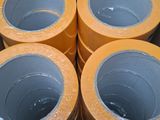 four rolls of yellow tape in a cardboard box on top of a table