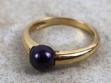 un gros plan d'une bague ornée d'une perle violette