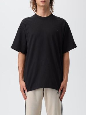 a man wearing a black t - shirt and beige pants