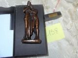 une statue en bronze représentant un homme et une femme, dans une boîte