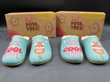 three pairs of blue slippers with hot dogs on them in front of a box