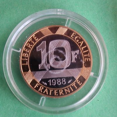 une pièce de monnaie dans un récipient en plastique posé sur une surface verte