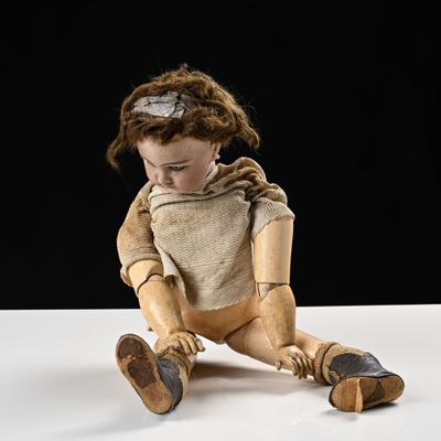 une poupée en bois posée sur une table, sur fond noir