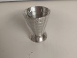 une petite tasse en argent posée sur un comptoir blanc
