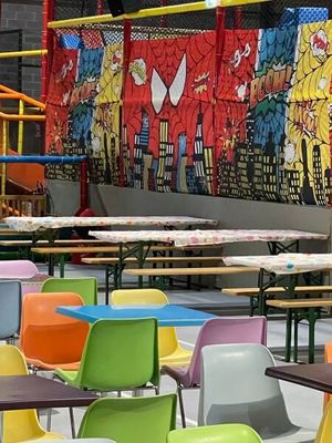 des tables et des chaises aux couleurs vives devant une fresque murale représentant des super-héros
