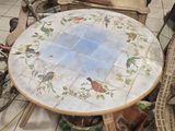 une table ornée d'un motif d'oiseau, avec une poupée assise dans un fauteuil en osier à côté