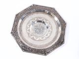 a silver plate with a design on it next to a remote control