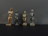 trois figurines en bronze représentant un homme et une femme, posées sur un fond noir
