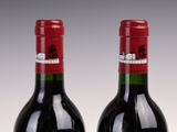 two bottles of red wine sitting next to each other on a table