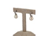 pair of pearl and diamond earrings on a stand on a white background