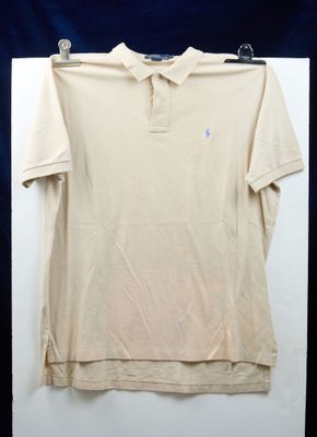 le polo est suspendu à un cintre devant un fond bleu
