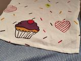 une couverture avec un cupcake dessiné dessus, posée sur un lit