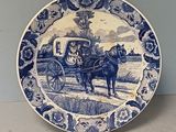 a blue and white plate with a horse drawn carriage on it