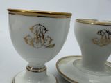 two cups and saucers with gold designs on them