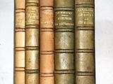 plusieurs vieux livres sont alignés sur une étagère, les uns à côté des autres