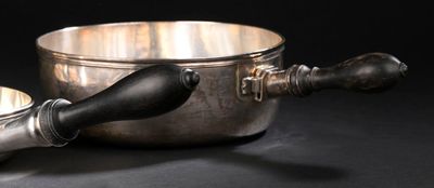 une casserole en argent et une cuillère en argent posées sur une table noire