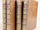 trois vieux livres posés l'un sur l'autre sur une surface blanche