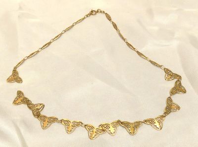 un gros plan d'un collier en or posé sur un tissu blanc