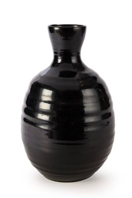 un vase noir posé sur une surface blanche