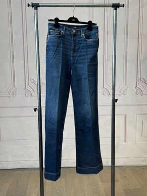 jeans hanging on a clothes rack in front of a white wall